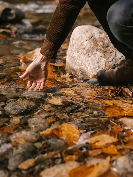 A hand touching a clear stream